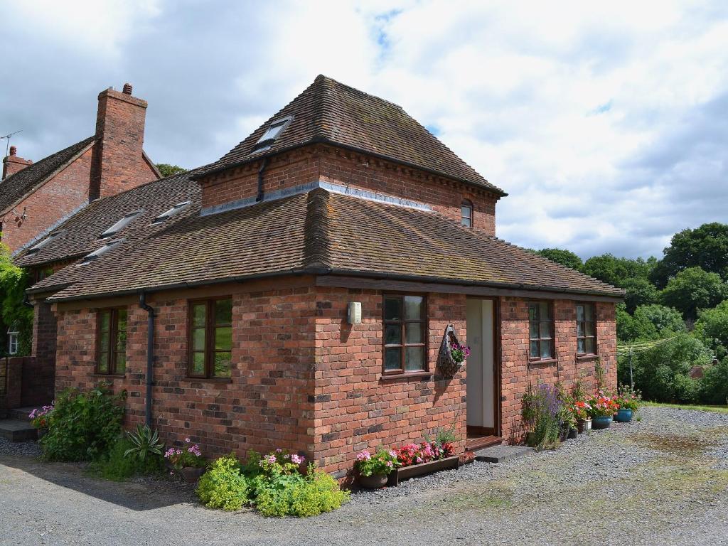 a small brick house with a roof at The Oast House in Boraston