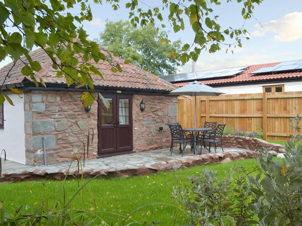 a patio with a table and chairs in a yard at Bluebell Cottage in Nether Stowey