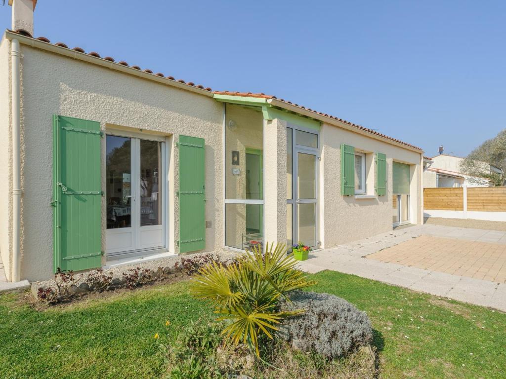 uma casa com portas verdes e um quintal em Maison Châtelaillon-Plage, 4 pièces, 6 personnes - FR-1-535-20 em Châtelaillon-Plage