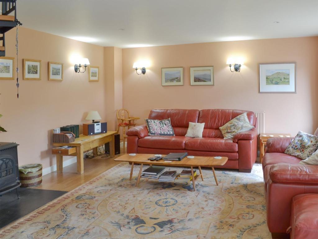 a living room with a red couch and a coffee table at Cherry Tree Cottage in Bovey Tracey