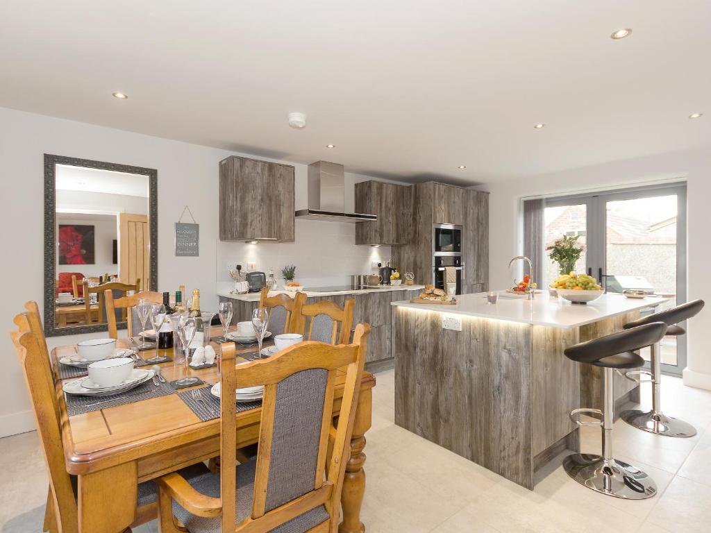 cocina y comedor con mesa de madera y sillas en Barn Owl Cottage en Skidby