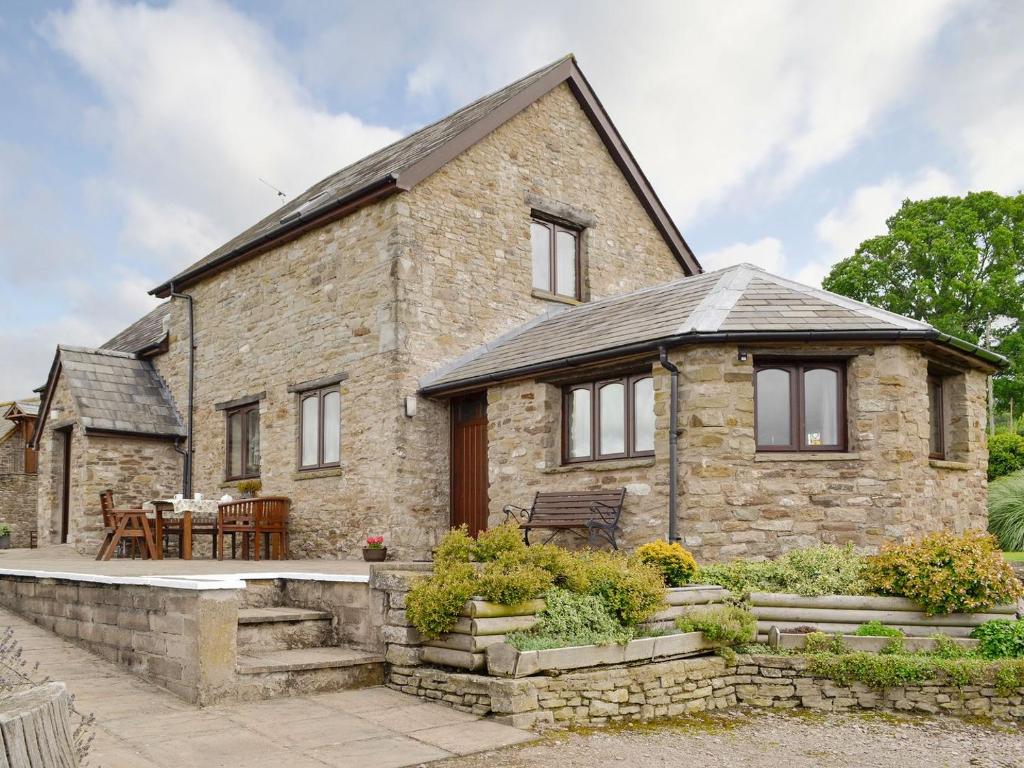 a stone house with a table and chairs in front of it at White Hill Farm Cottage in Dingestow