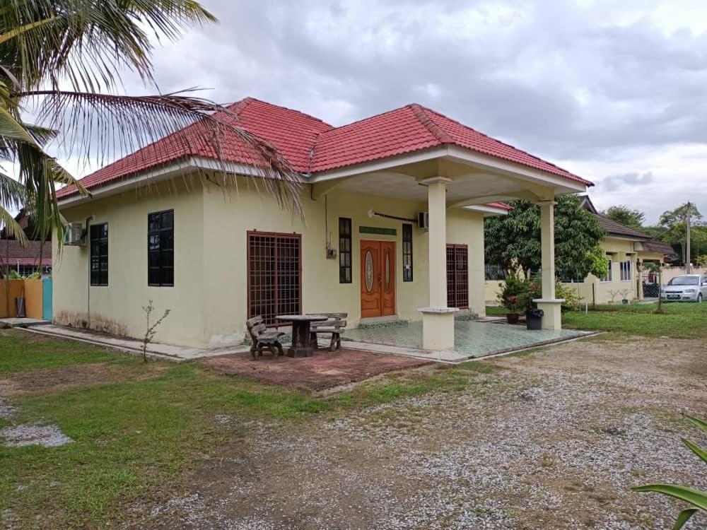 una pequeña casa blanca con techo rojo en HOMESTAY JANNATI TAMBUN, en Tambun