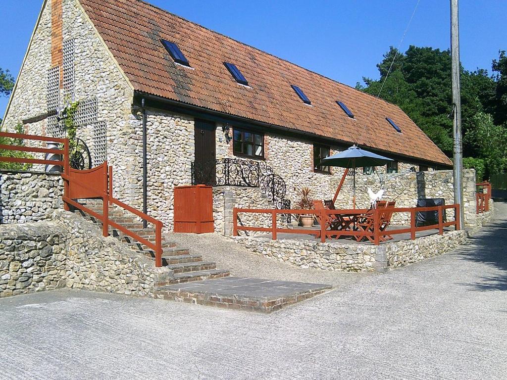 a stone building with benches and a table and an umbrella at Cider Cottage in Hawkchurch