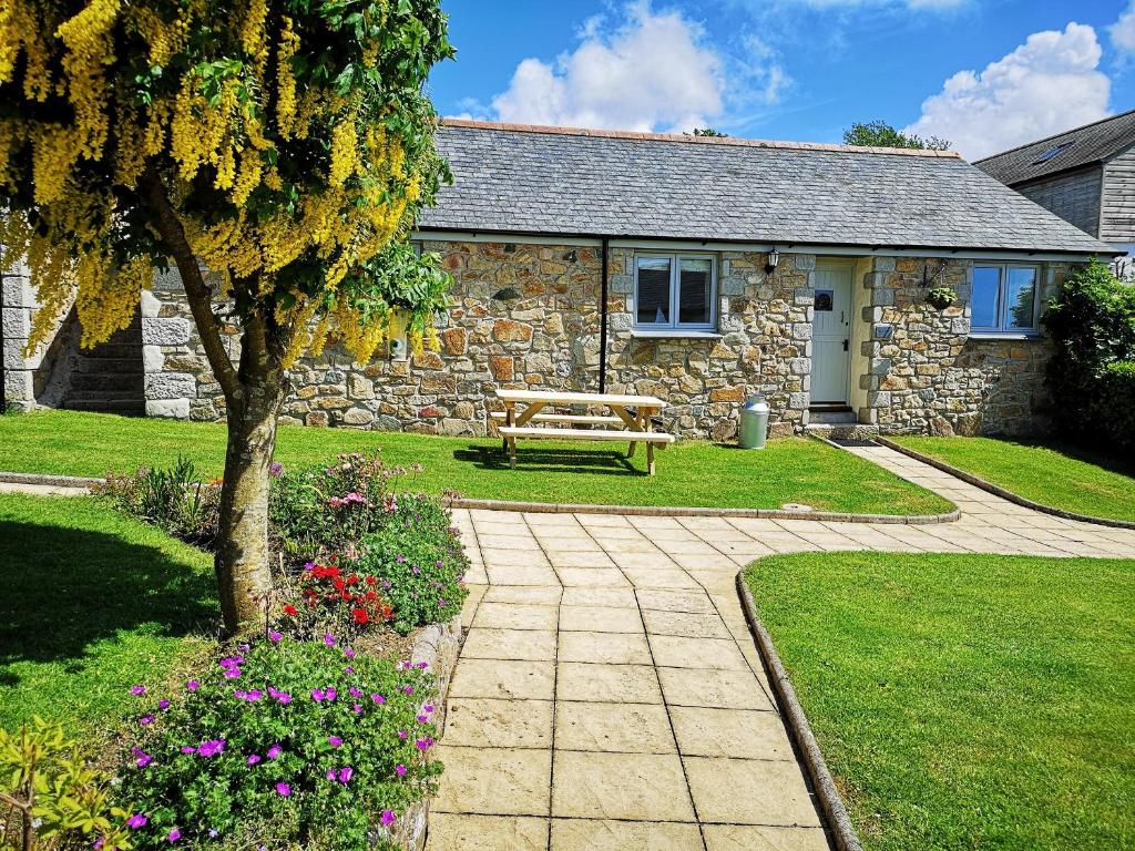 una casa de piedra con un banco delante en Maple Barn en Porthtowan