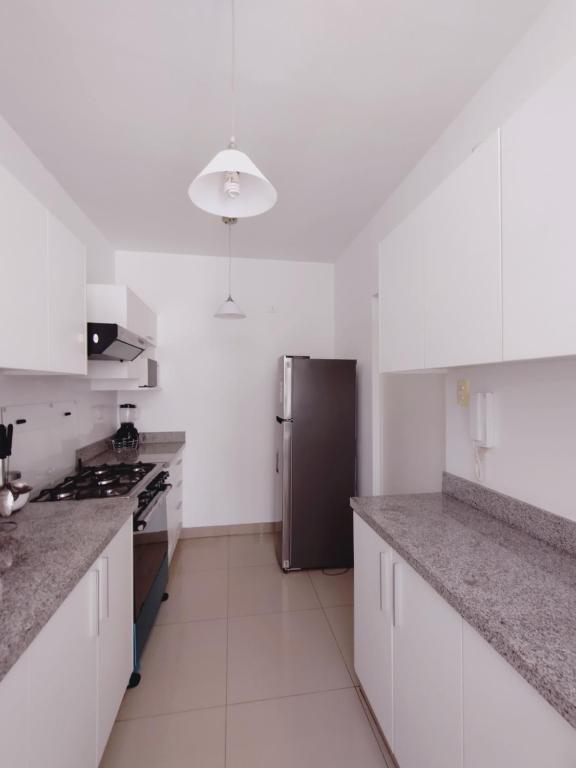 a kitchen with white cabinets and a stainless steel refrigerator at Acogedor Departamento 3 Hab Piura in Piura