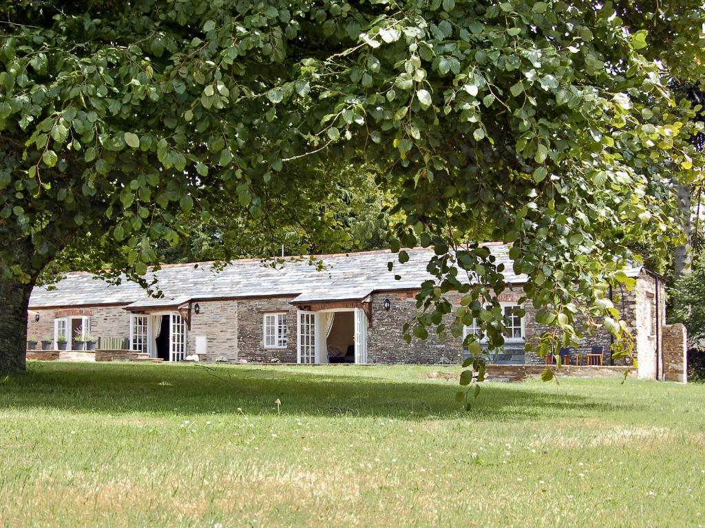 une vieille maison en briques dans un champ avec un arbre dans l'établissement Game Larder Cottage, à Saint Mabyn