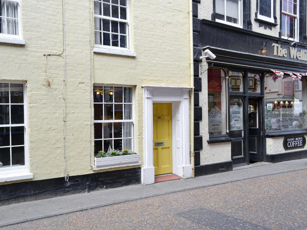 a couple of buildings with a yellow door on a street at Seashells in Cromer