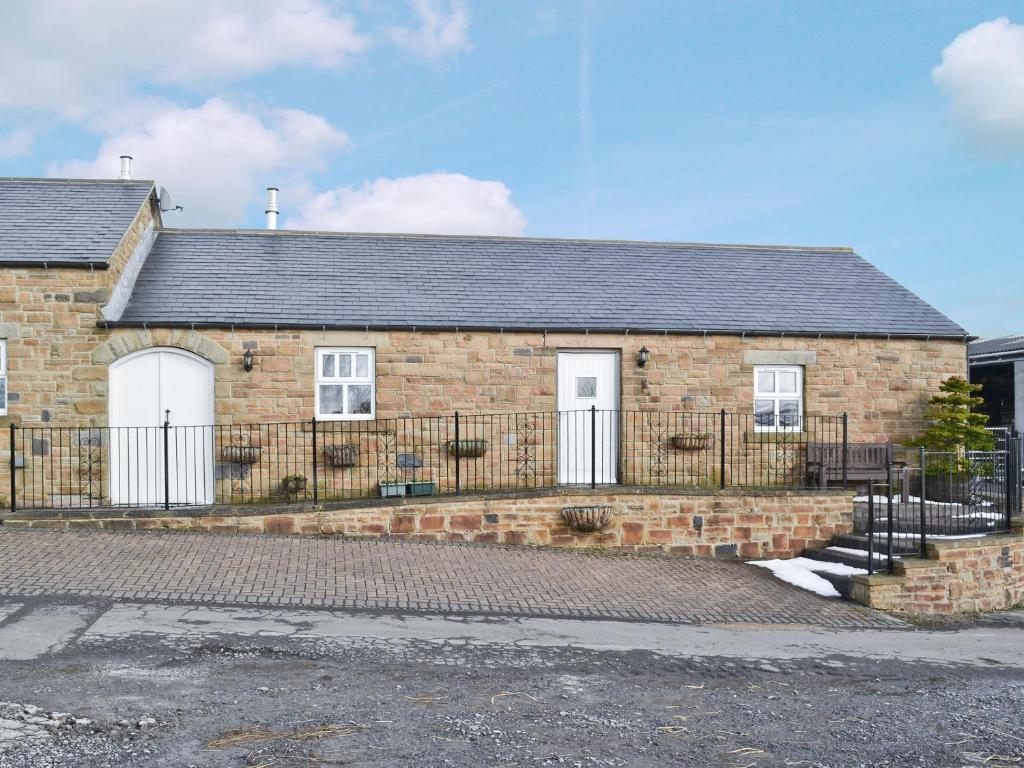 a brick house with a fence in front of it at Alices Cottage in Lanehead