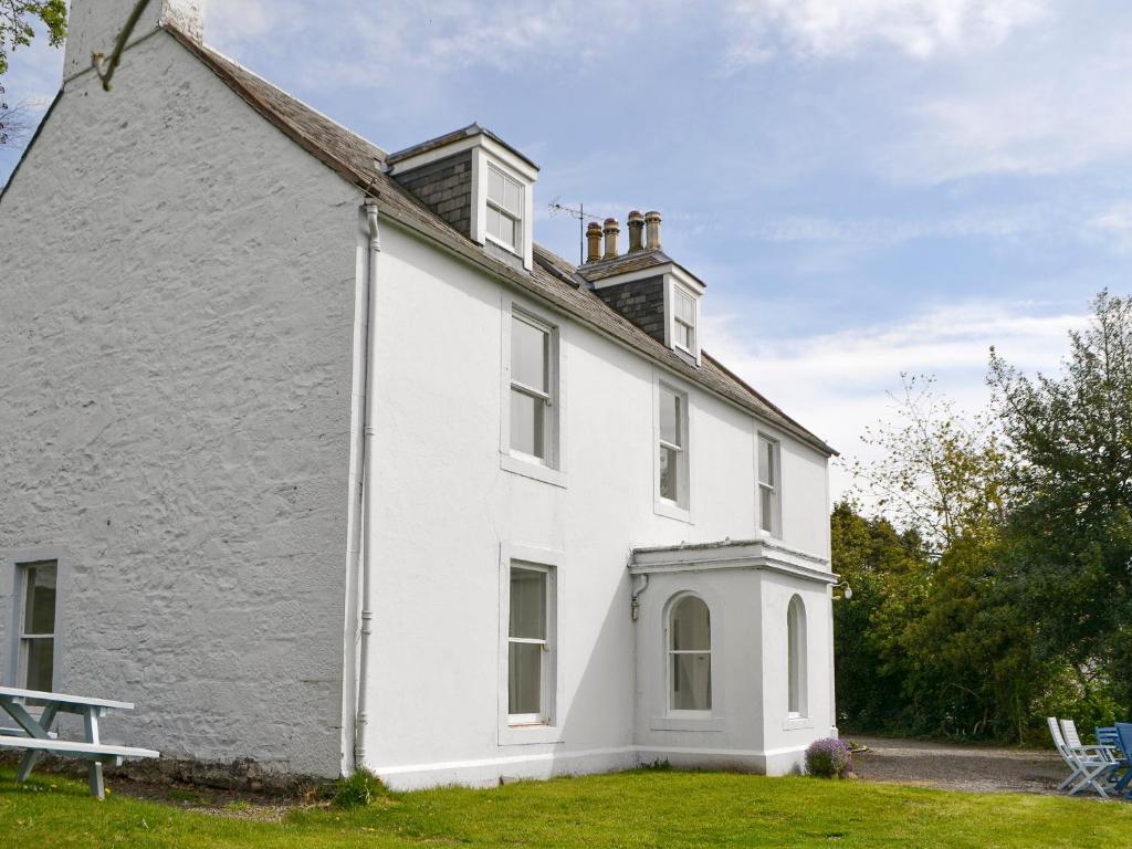 a white house with a bench in front of it at Burnfoot Of Cluden in Holywood