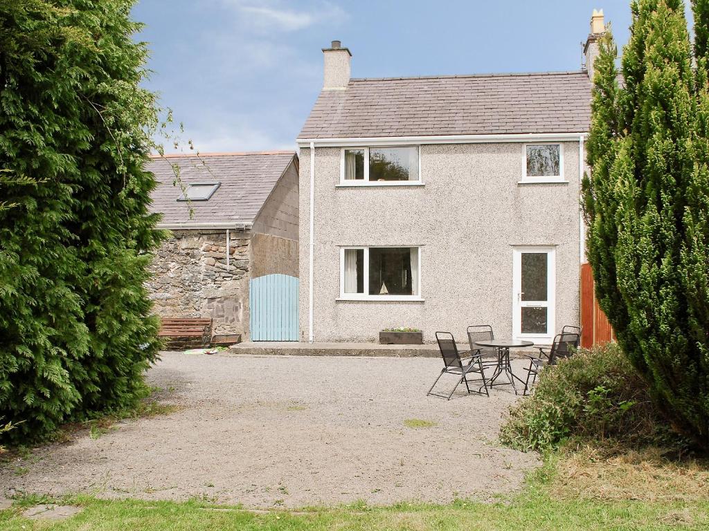 a house with chairs and a table in front of it at Y Bwthyn in Llangristiolus