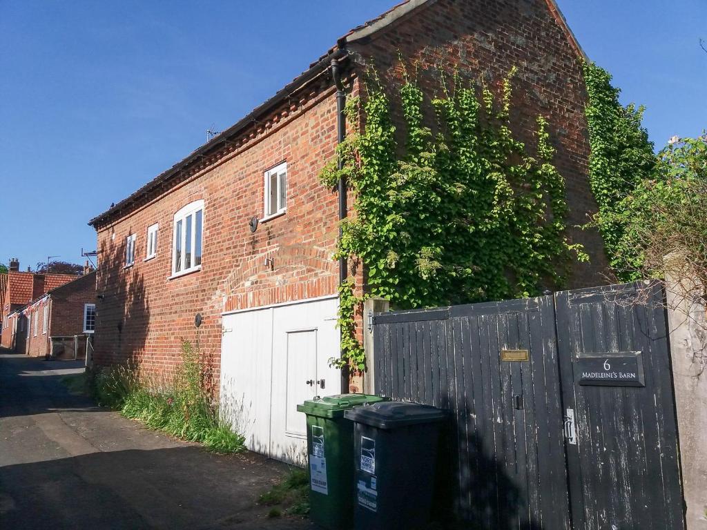 a brick building with two trash cans in front of it at Madeleines Barn in Wells next the Sea