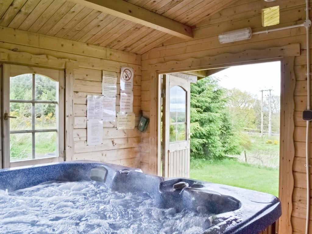 eine Badewanne in einem Blockhaus mit Fenster in der Unterkunft Fingask Log Cabin - S4394 in Glenfarg