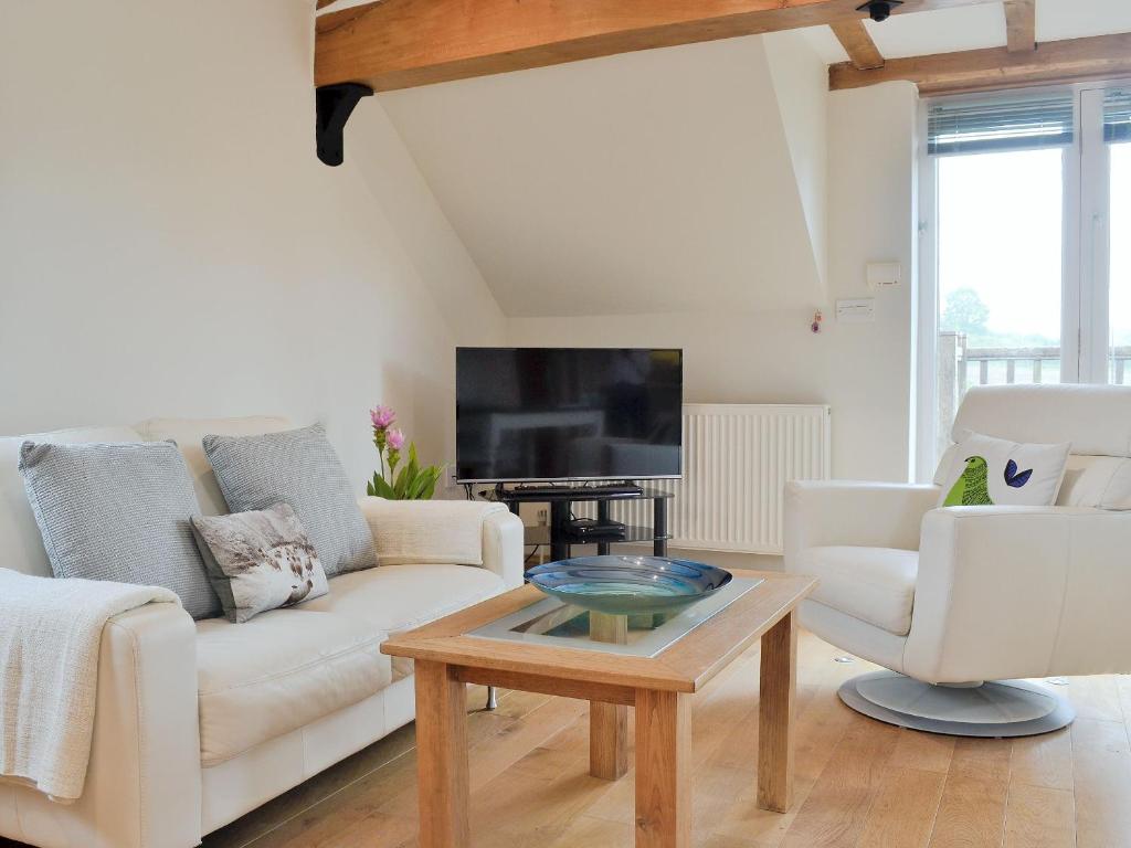 a living room with a white couch and a coffee table at Hurdlemakers Loft in Upper Brailes