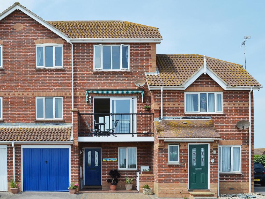 a brick house with blue doors and a balcony at Bay View in Clacton-on-Sea