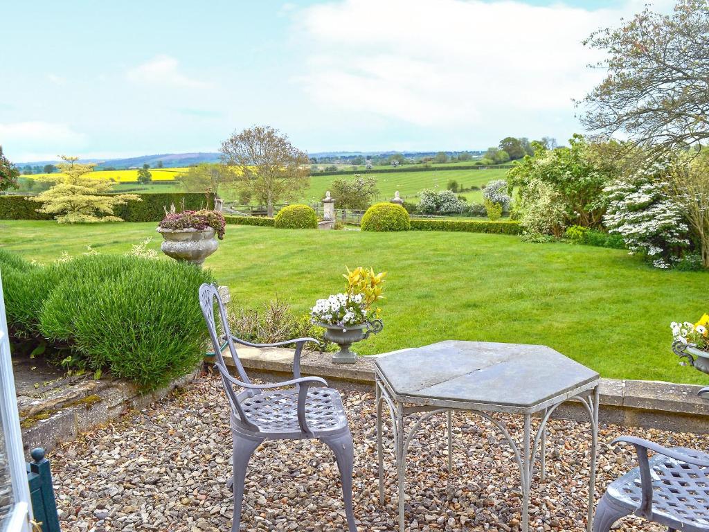 um jardim com uma mesa e cadeiras e um relvado em Acorn Cottage em Todenham