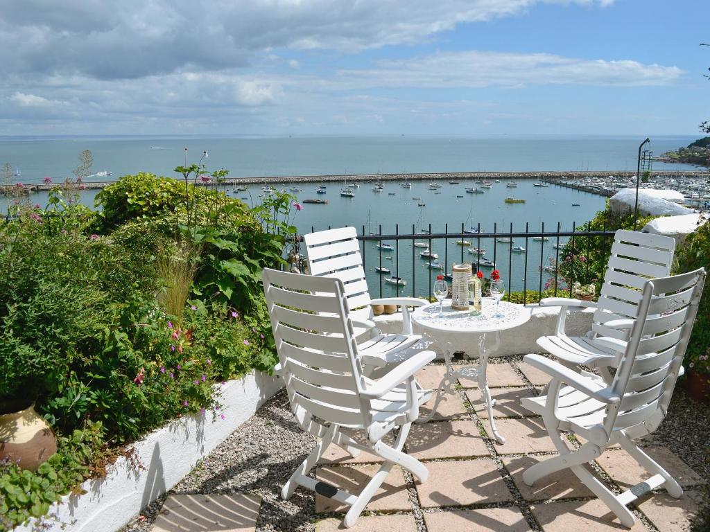 een witte tafel en stoelen met uitzicht op de oceaan bij Seaside Stories in Brixham