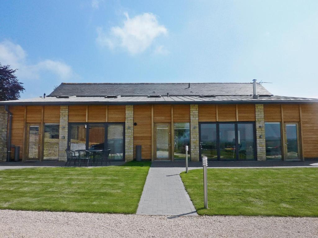 a wooden house with a lawn in front of it at The Hayloft - Nab in Aynho