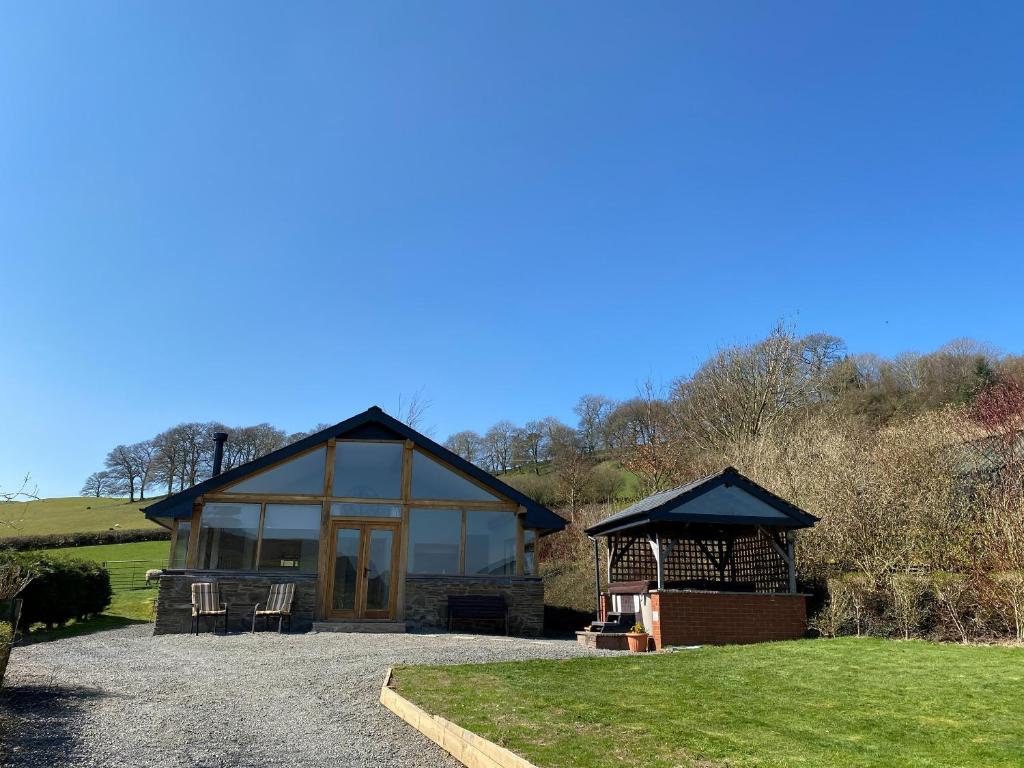 a small house with a large window and a gazebo at Oak View Cottage in Llangunllo