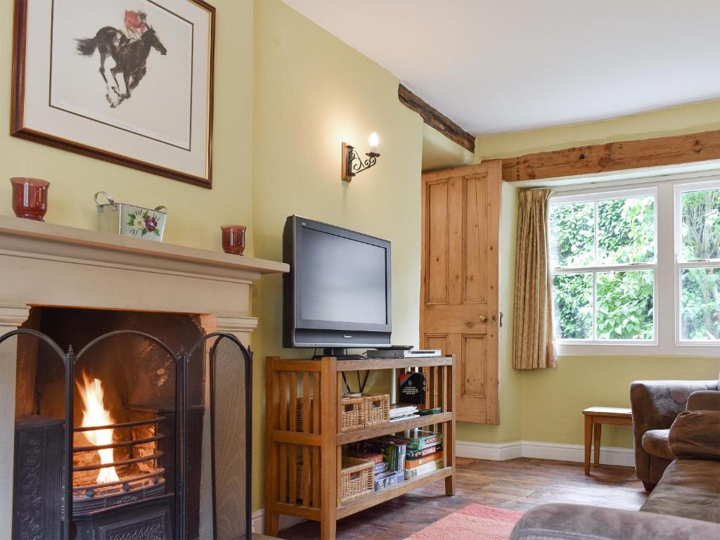 a living room with a fireplace and a tv at Dove Cottage in Middleham