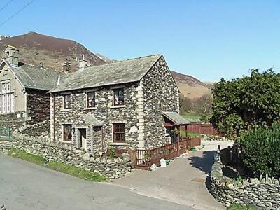 an old stone house with a stone wall at Apple Tree Cottage in Threlkeld