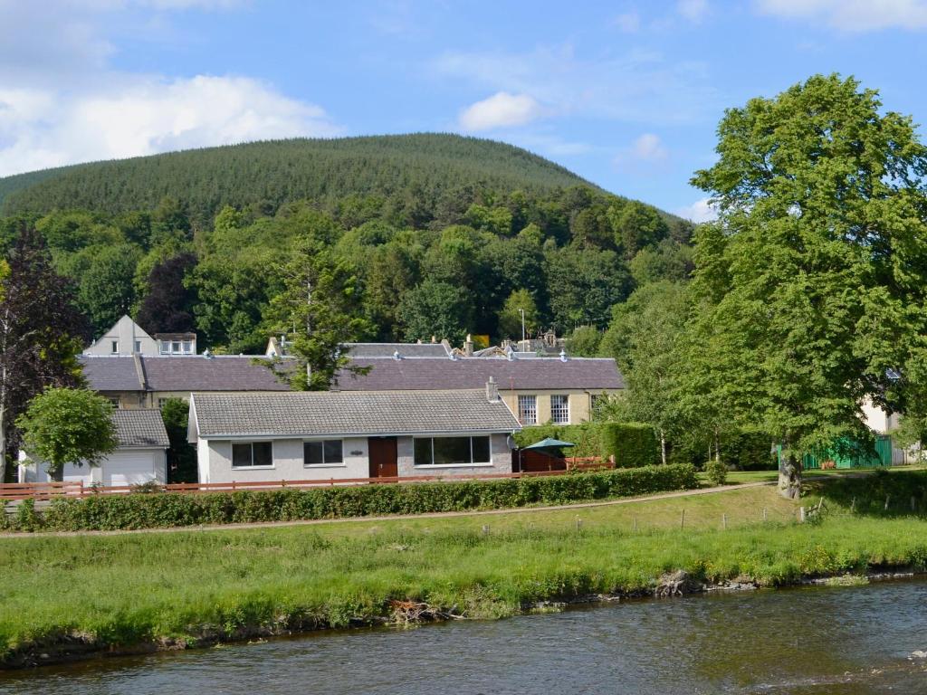a house on the river with a mountain in the background at Bydand in Walkerburn