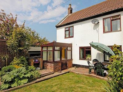 a white house with a table and chairs in a yard at Beach Cottage in Winterton-on-Sea