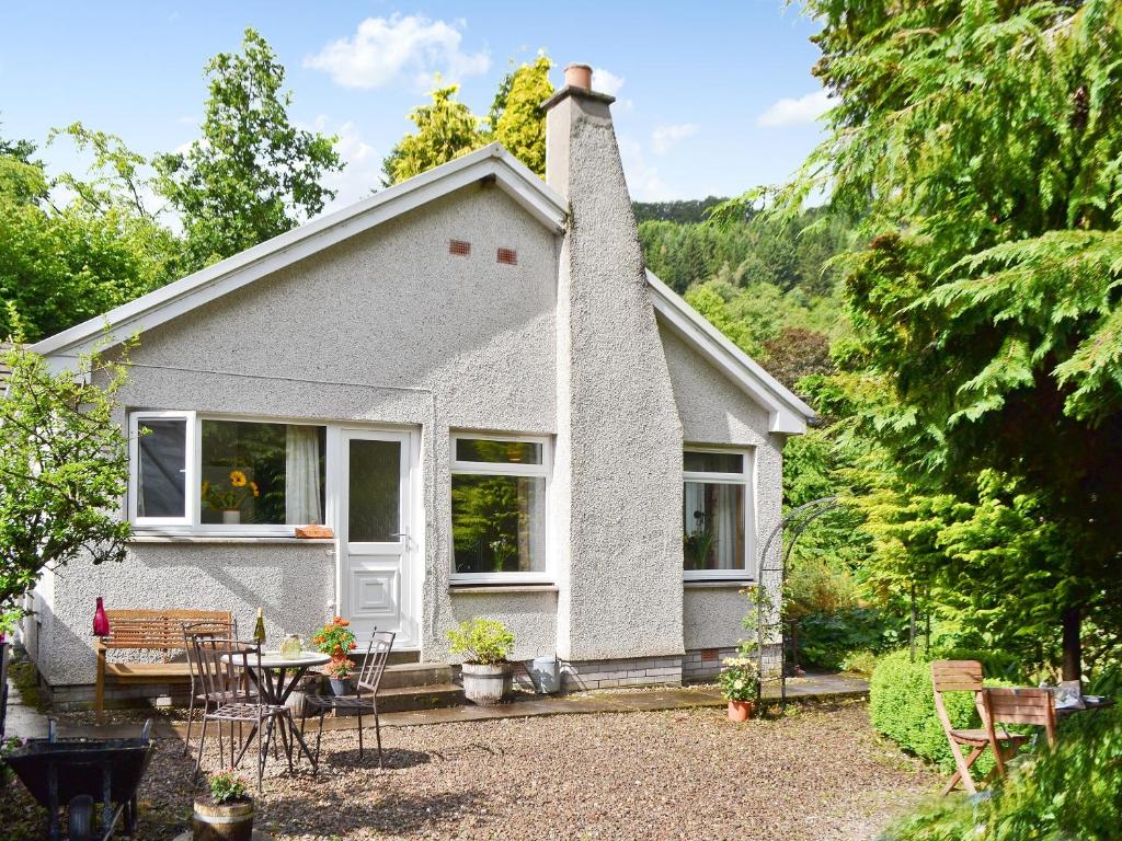 a small house with a chimney and a table and chairs at Tigh Nan Allt in Dull