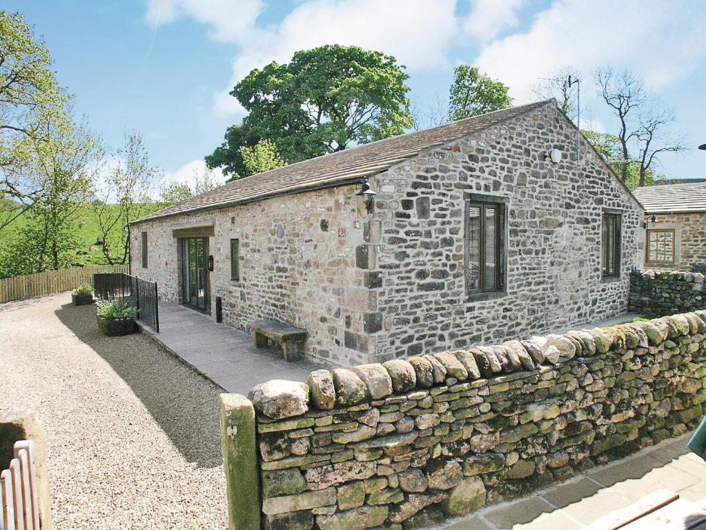 an old stone building with a stone wall at Grisedale Coach House in Threshfield