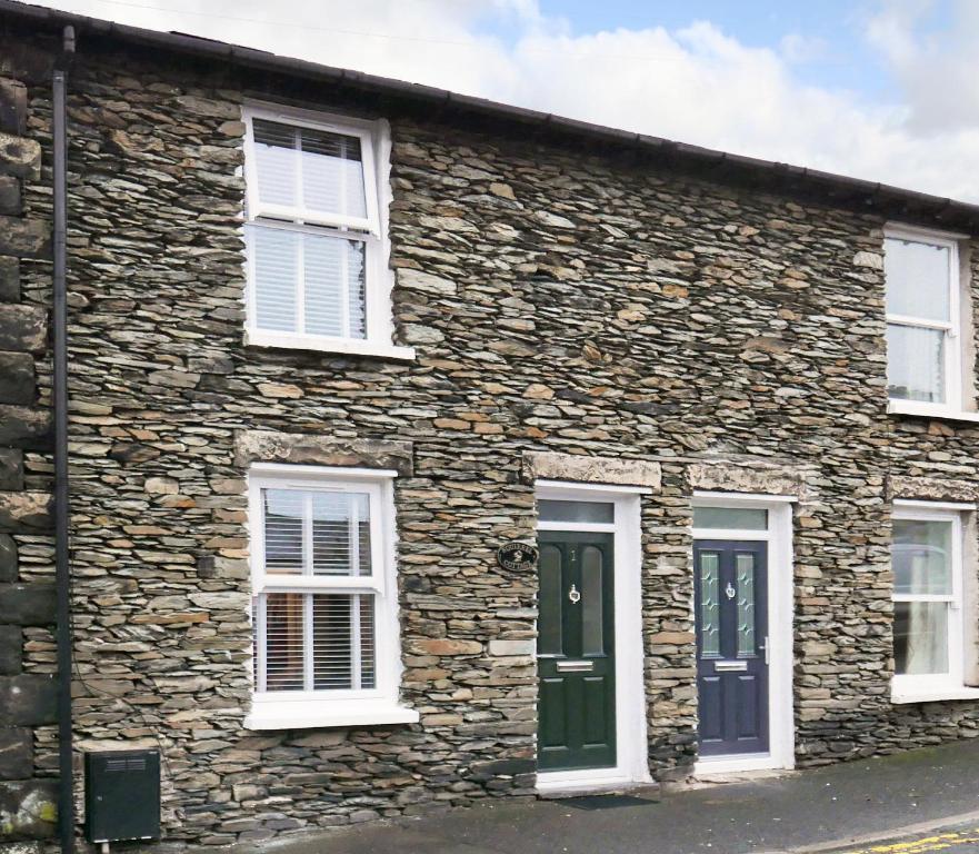 a stone house with white windows and green doors at Squirrel Cottage in Windermere