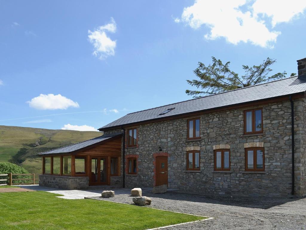 una casa de piedra con un patio de hierba delante de ella en Gorsddu, en Llanwrthwl