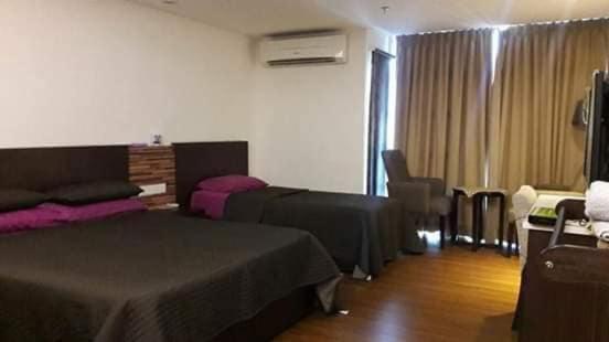een hotelkamer met 2 bedden en een raam bij d arissa house in Kota Bharu