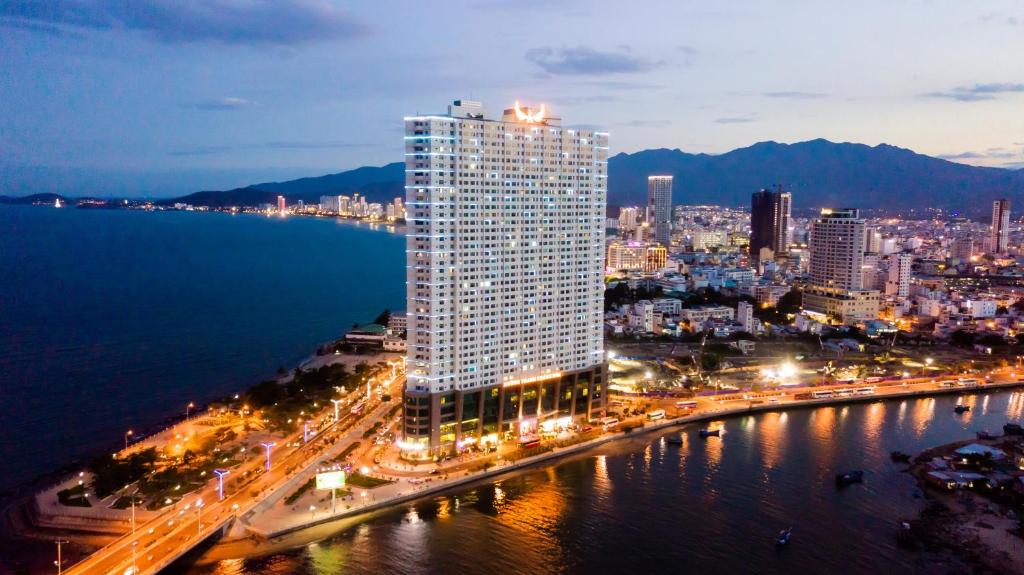 a tall building next to the water at night at Muong Thanh Luxury Khanh Hoa in Nha Trang