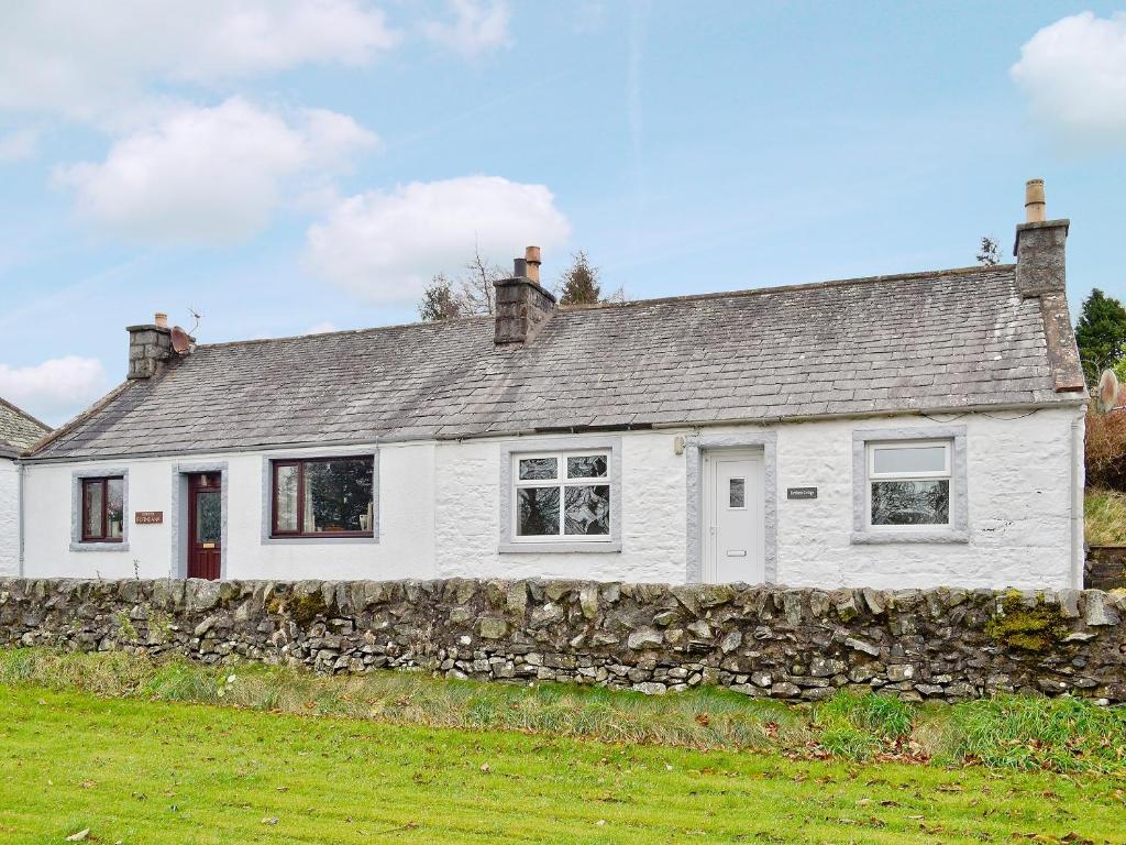 a white house with a stone wall at Burnbank in Kirkgunzeon