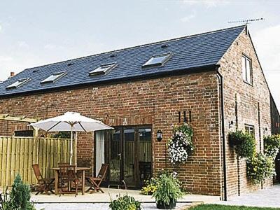 una casa de ladrillo con mesa y sombrilla en Eaton Barn, en Burmarsh