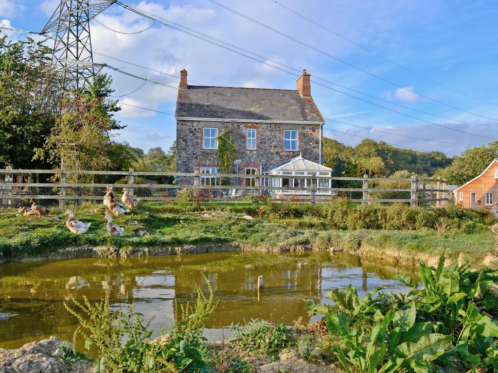 an old stone house with a pond in front of it at Dunley Farmhouse in Bovey Tracey