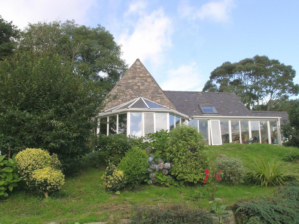 Holly Cottage - 28140 في Boreland of Colvend: منزل مع حديقة شتوية على تلة مع النباتات