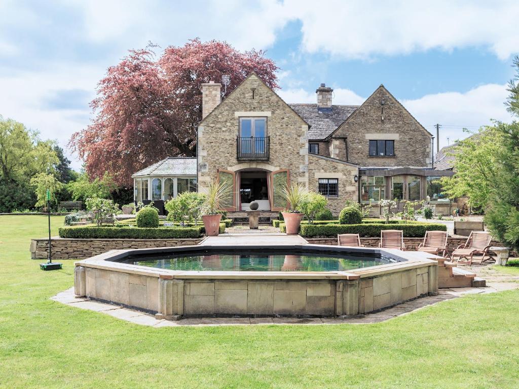 an estate with a pool in front of a house at Cotswolds Farm in Miserden