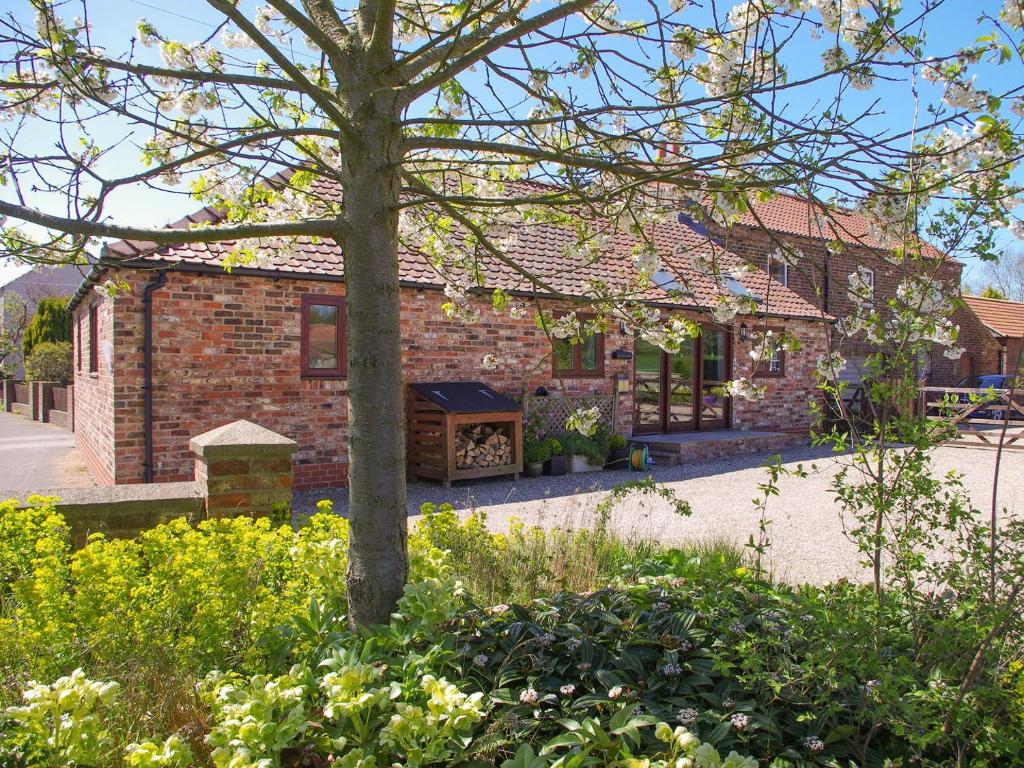 a brick house with a tree in a garden at The Old Forge in West Lutton