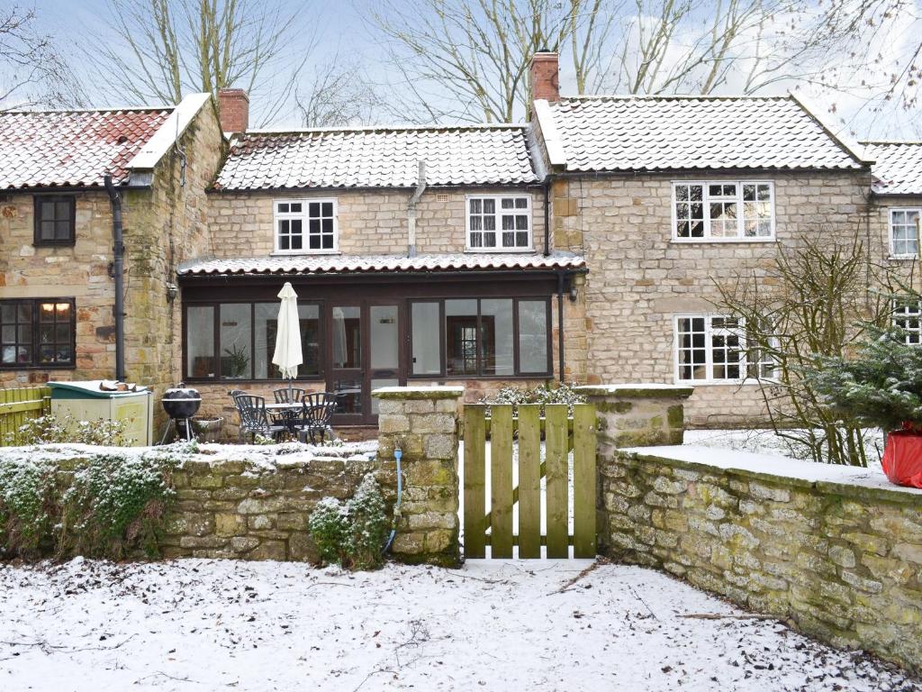 a brick house with a fence in the snow at Brewers Cottage in Cropton