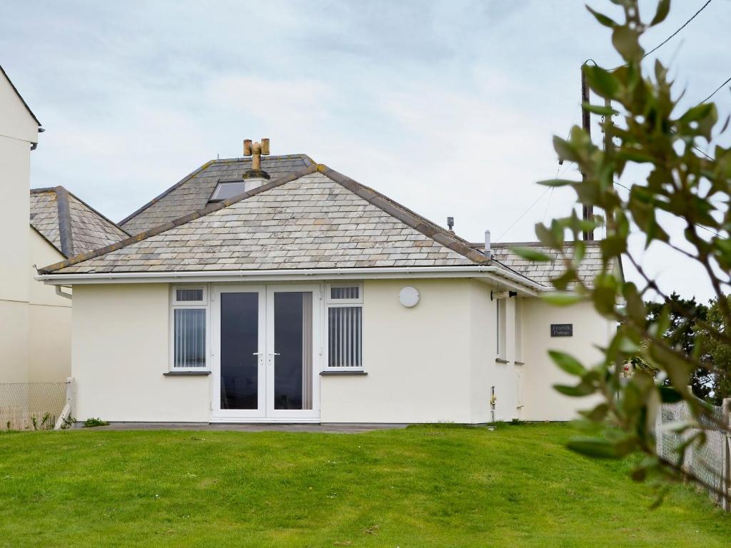 a white house with a lawn in front of it at Freefolk Cottage in Polzeath