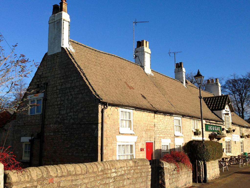 un bâtiment en briques avec deux cheminées au-dessus dans l'établissement Jug And Glass Cottage, à Upper Langwith