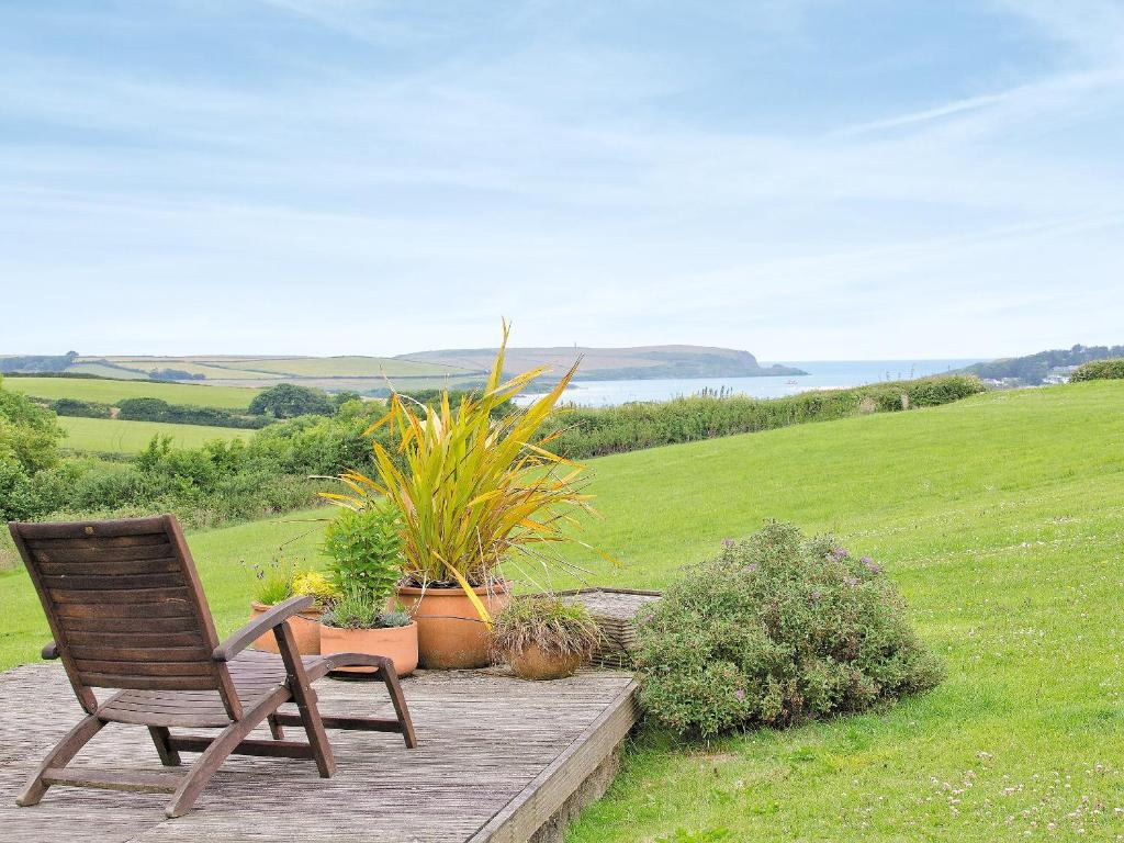 a wooden chair sitting on a wooden deck with plants at The Linhay in Little Petherick