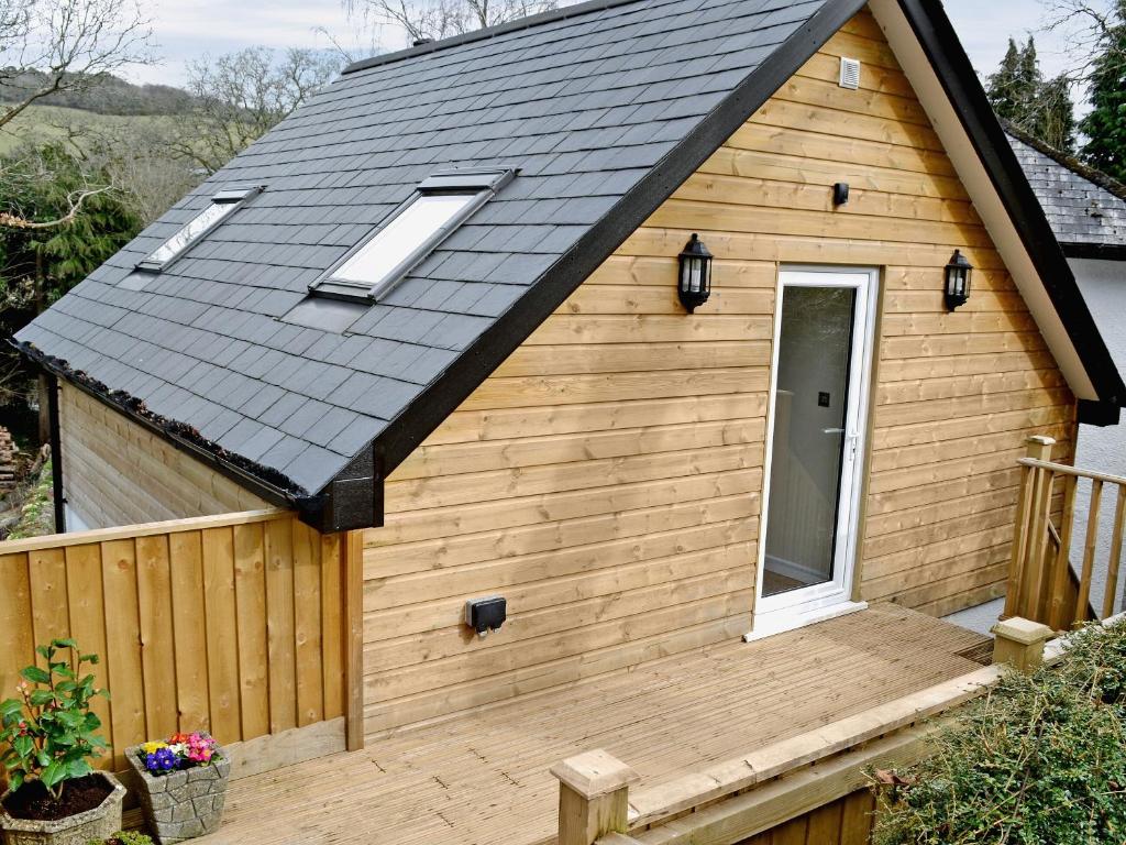 a tiny house with a black roof and a wooden deck at Magpies Rest in Horrabridge