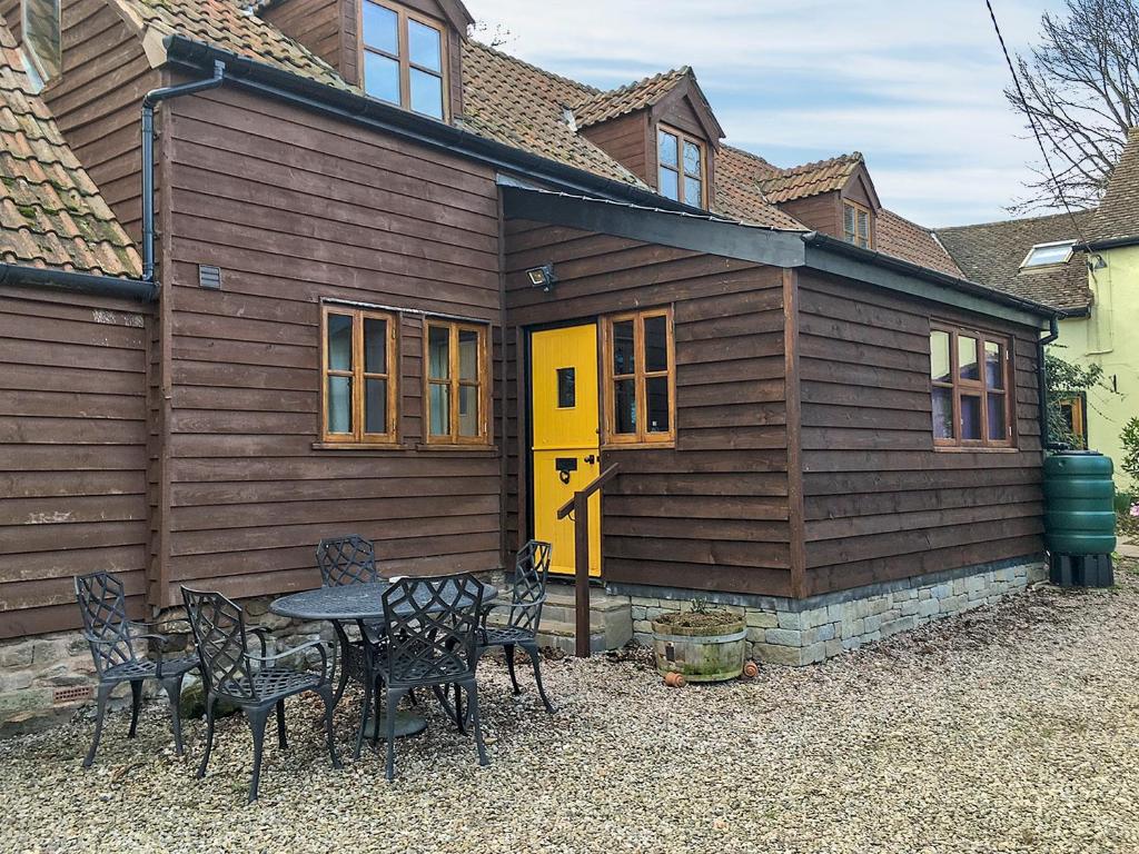 una casa con una porta gialla e un tavolo con sedie di Stocks Tree Cottage a Preston Wynne