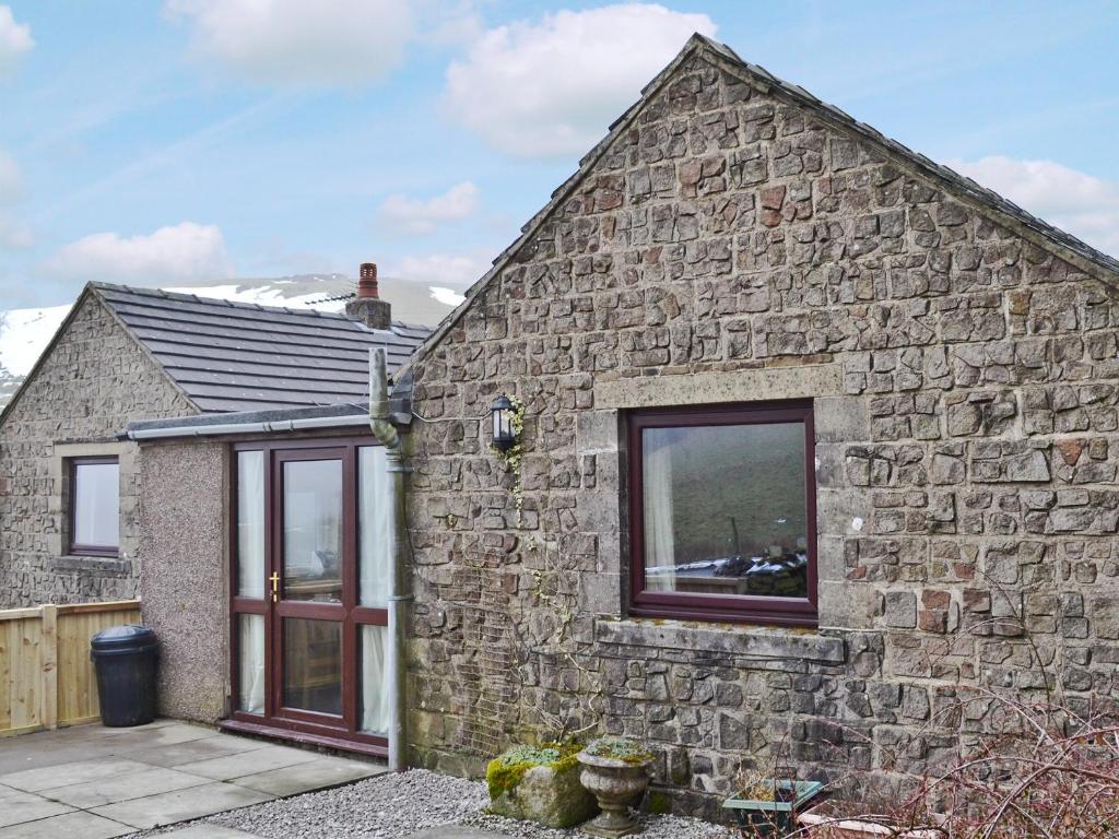 a stone house with a large window on the side of it at Booth Farm Bungalow in Hollinsclough