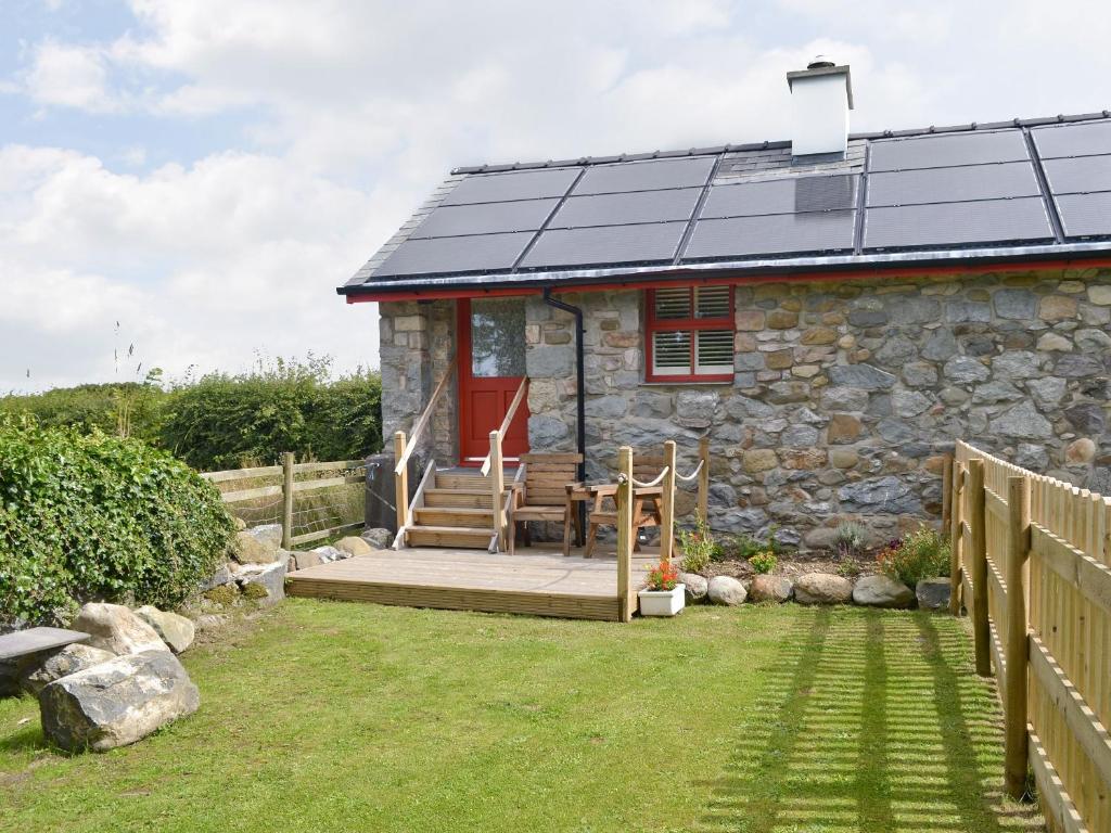 a small stone cottage with a red door and a porch at Ty Sam in Llanwnda