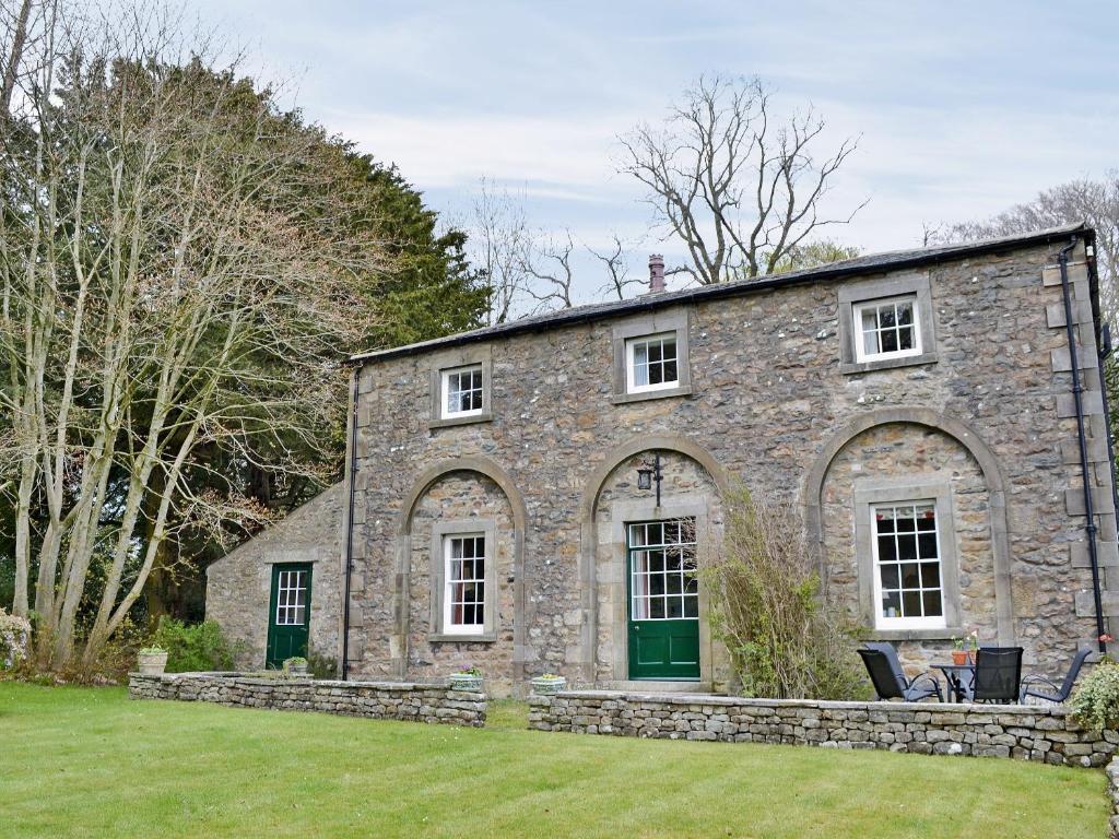 an old stone house with a green door at The Court House in Cowan Bridge