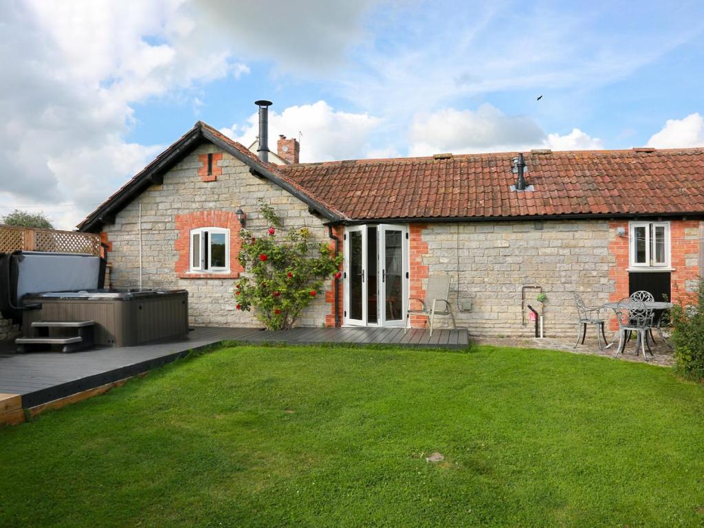 une maison en briques avec une pelouse devant elle dans l'établissement The Cottage, à South Barrow