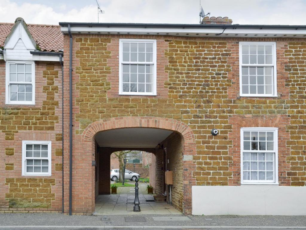 una entrada a un edificio de ladrillo con un arco en Trentham Cottage, en Snettisham